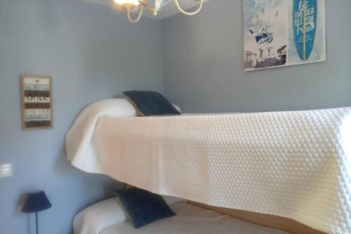 a white bed with blue pillows in a room at Centrico apartamento en Noja con acceso a Spa in Noja