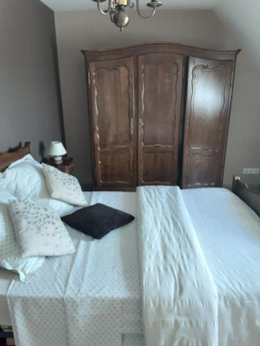 Schlafzimmer mit einem weißen Bett mit einem Kopfteil aus Holz in der Unterkunft Chambre d'hôtes de la Galie in Sainte-Marie-du-Mont