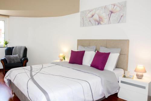 een slaapkamer met een groot wit bed met paarse kussens bij Sol do Lido in Funchal