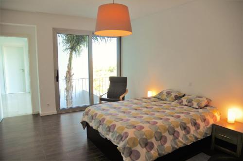 a bedroom with a bed and a chair and a window at Spacious sunset Villa with breathtaking view in Portimão