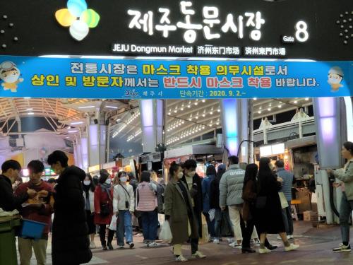 a crowd of people standing outside of a market at Jeju Vision House in Jeju