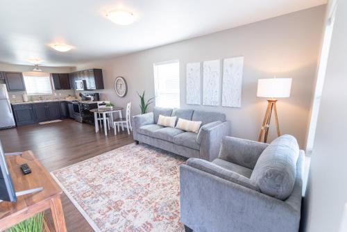 a living room with two couches and a kitchen at Susitna Suites in Wasilla