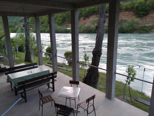 a porch with a table and chairs next to a river at Prenoćište na Drini Foča in Foča