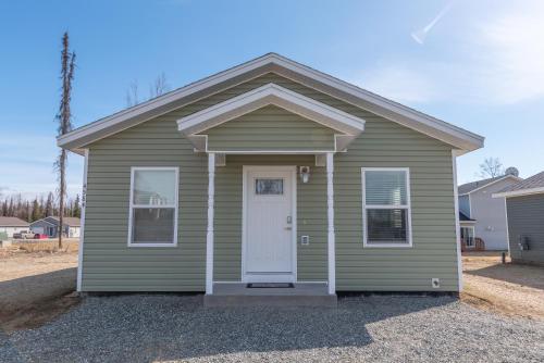 a small green house with a white door at Susitna Suites in Wasilla