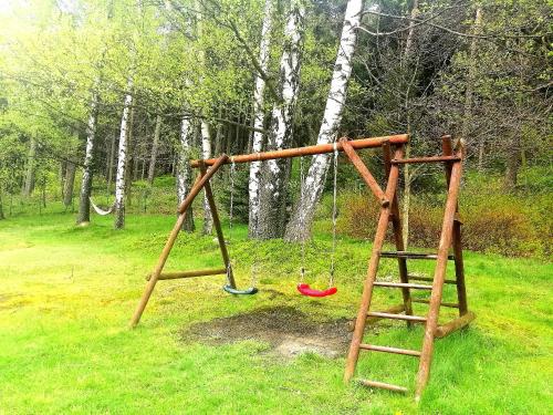 a wooden swing set in a field with trees at Tyrolska Chata in Świeradów-Zdrój