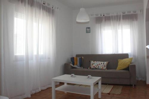 a living room with a couch and a table at Casa das Flores in Vila do Bispo