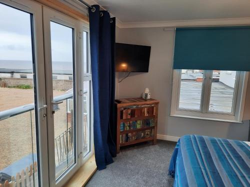 a bedroom with a balcony with a bed and a television at Seals Bacton in Bacton