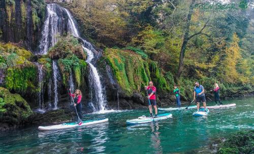 a group of people on paddle boards in the water near a waterfall at Apartmani ZELENI MEDA in Mitrovac