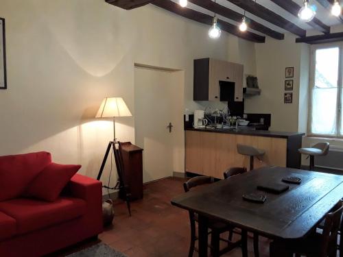 un salon avec un canapé rouge et une table dans l'établissement La petite Bardouillère, à Courdemanche