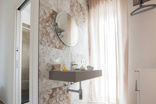 baño con lavabo y espejo en la pared en B&B IL SOGNO, en Rocca Imperiale
