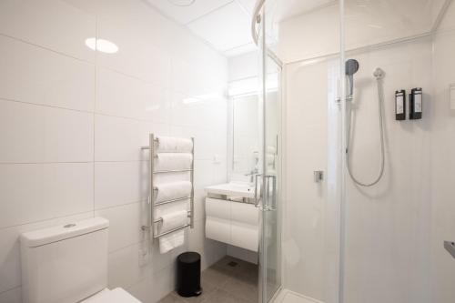 a white bathroom with a shower and a toilet at Sojourn Apartment Hotel - Riddiford in Wellington