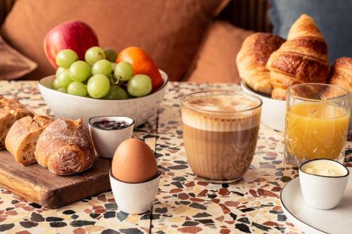 un tavolo con colazione a base di pane e prodotti da forno di Hôtel Maison Traversière a Parigi