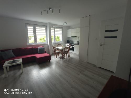un salon avec un canapé rouge et une table dans l'établissement Apartament Blisko Zamku, à Malbork