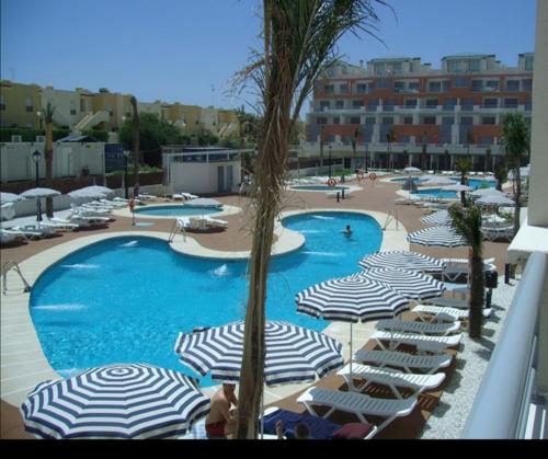 una gran piscina con sombrillas y sillas en un complejo en Marina Rey Aparthotel, en Vera