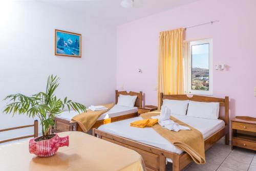 a hotel room with three beds and a window at Arsinoi Studios and Apartments in Kalamaki