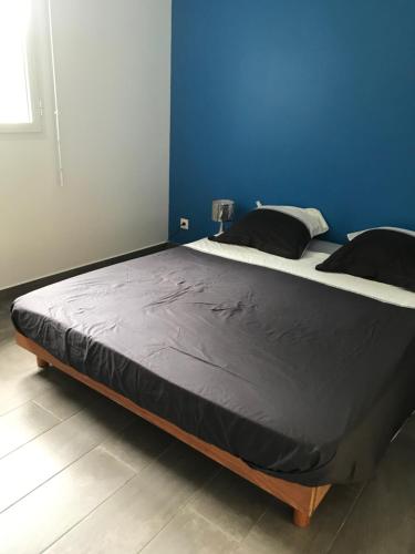 ein großes Bett in einem Zimmer mit blauer Wand in der Unterkunft BUNGALOW LOLOTTE ET DOM in Sainte-Anne