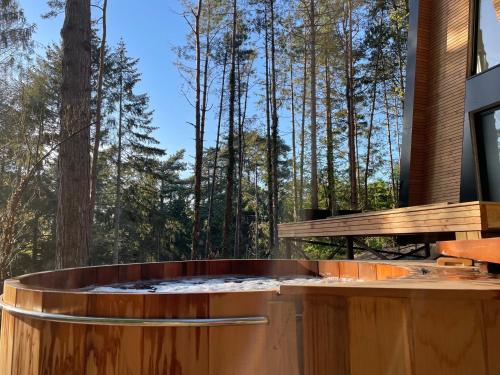 a hot tub on a deck with trees in the background at Bain de forêt - Lodges Cosy & Spa in Neufchâtel-Hardelot