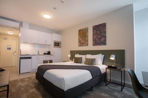 a bedroom with a large bed and a kitchen at Sojourn Apartment Hotel - Riddiford in Wellington