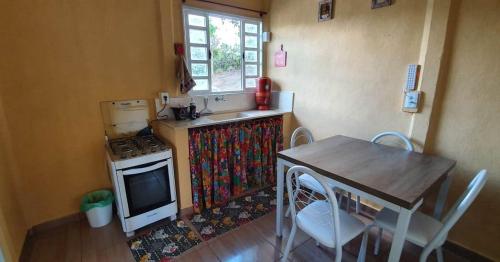 uma cozinha com uma mesa, um fogão, uma mesa e cadeiras em CASA GIRASSOL-Trilha das Flores-SERRA DA CANASTRA em São Roque de Minas