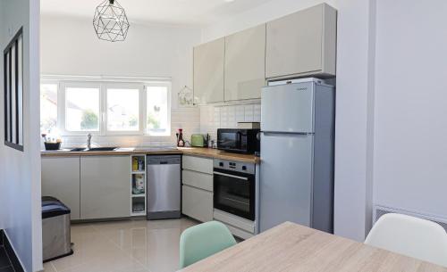 una cucina con armadietti bianchi e frigorifero di LE Repaire Du Capitaine a Chanteloup-les-Vignes