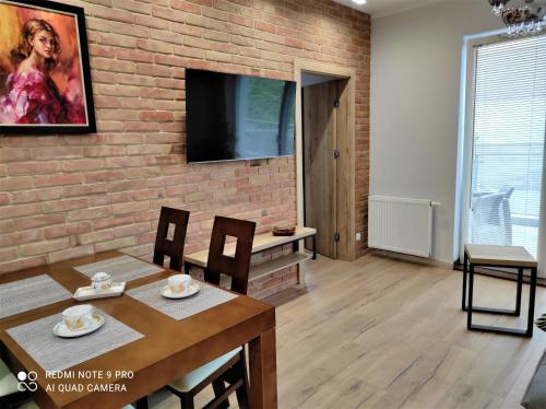 a living room with a brick wall and a table and chairs at MAZURSKA DAMA LUXURY APARTAMENT in Giżycko