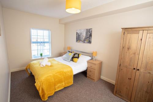 ein Schlafzimmer mit einem Bett mit einer gelben Decke in der Unterkunft Ample Comforts, Centrally Located, Town Centre in Warrington