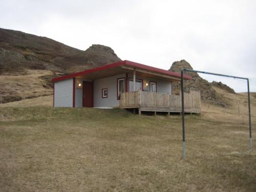 a small house in a field with a hill at Ásbrandsstadir Cottages in Vopnafjörður