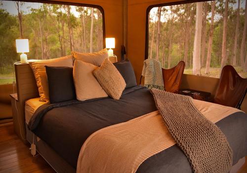 ein Schlafzimmer mit einem Bett mit Kissen und einem Fenster in der Unterkunft Ketchup's Bank Glamping in Boonah