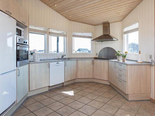 a large kitchen with white appliances and wooden ceilings at 8 person holiday home in Harbo re in Harboør
