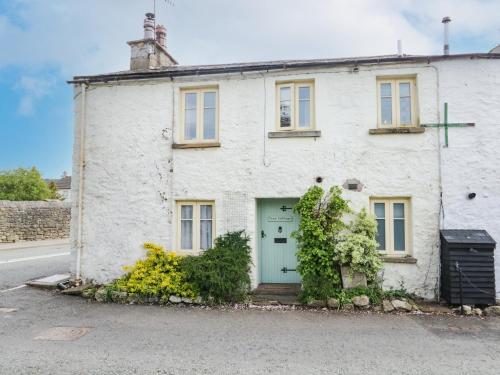 a white brick house with a green door at Tyee Cottage in Carnforth