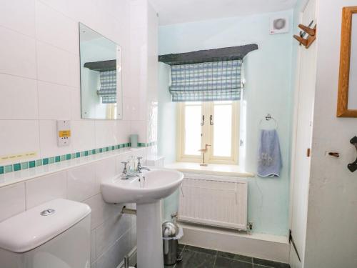 a white bathroom with a sink and a toilet at Tyee Cottage in Carnforth