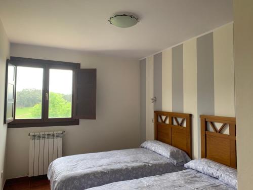 a bedroom with two beds and a window at Apartamentos La Peral in La Peral