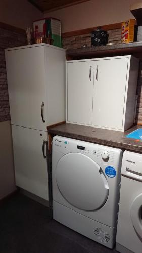 a kitchen with a washer and a white cabinet at Enlli Fach cabin sleep's 2 adults and 2 children 2 dogs welcome not suitable for contract workers due to parking height restrictions in Borth