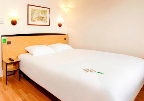 a bedroom with a large white bed and a table at Campanile Manosque in Manosque
