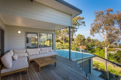 a living room with a couch and a table on a deck at ADS on Collins - 4 bedroom and Pet Friendly in Merimbula