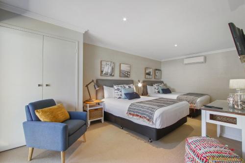 a hotel room with two beds and a chair at McMillans of Metung Coastal Resort in Metung