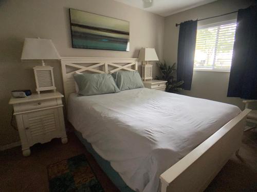a bedroom with a large white bed and two night stands at Elegant 1 Bedroom Condo With Swimming Pool Gym Access All Included In Convenient Fort Myers Location Near Golf Courses and Sanibel Island in Fort Myers