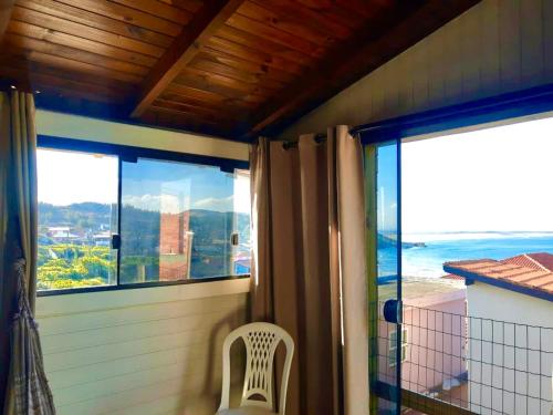 a room with a balcony with a view of the ocean at Chalês Santa Marta in Farol de Santa Marta