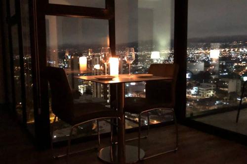 a table with wine glasses and a view of a city at Amazing views SJO, Cozy, Equipped. 24/7 Concierge in San José