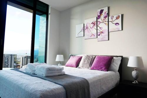 a bedroom with a bed with purple and pink pillows at Amazing views SJO, Cozy, Equipped. 24/7 Concierge in San José