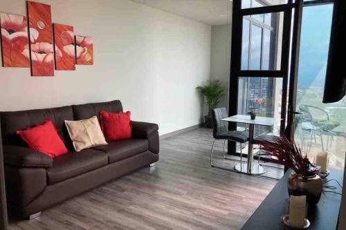a living room with a brown couch and a table at Amazing views SJO, Cozy, Equipped. 24/7 Concierge in San José