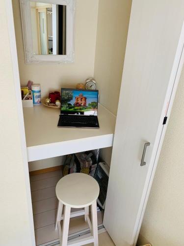 a laptop computer sitting on a desk with a stool at COCO Nakameguro 201 in Tokyo