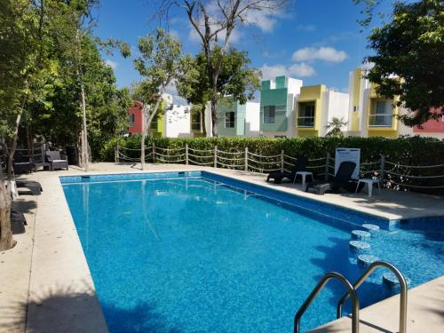 a swimming pool with blue water in front of a building at CasaMEXH Veredas - Ideal para familias, vacaciones o homeoffice a10 min de la playa in Puerto Morelos