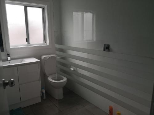 a bathroom with a toilet and a sink and a window at So close to Birubi Beach in Anna Bay