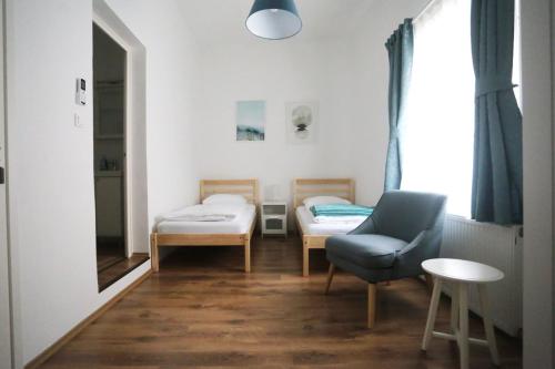 a room with two beds and a chair and a window at Jókai 19 Vendégház in Veszprém