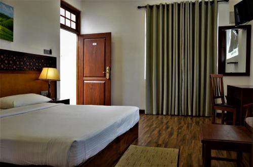 a bedroom with a bed and a desk and a door at Heaven Seven Nuwara Eliya in Nuwara Eliya