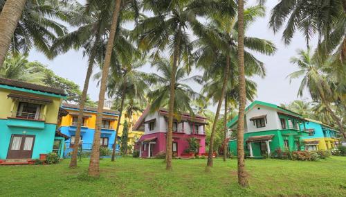 a row of colorful houses with palm trees in a field at Miramar Residency in Panaji