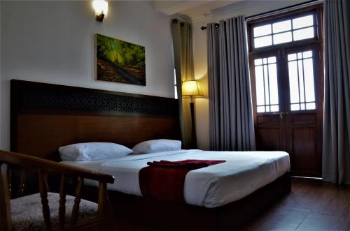 a bedroom with a bed and a window and a door at Heaven Seven Nuwara Eliya in Nuwara Eliya