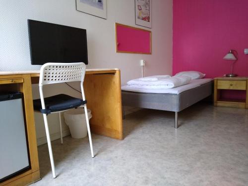 a bedroom with a bed and a desk with a television at Hotell Milano in Åstorp