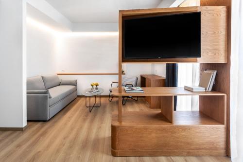 sala de estar con TV de pantalla plana en un centro de entretenimiento de madera en DAYS City Suites en Patras
